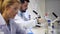 Mature scientist chatting with colleague while examining sample in laboratory