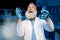 Mature scientist in lab coat holding flask with reagent at laboratory