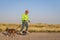 Mature senior male is riding one-wheeled electric skateboard  with a dog