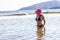 Mature sexy woman cools off in the sea in black bikini and red hat