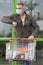 Mature smiling man with face mask greets another person with his elbow while leaving a supermarket with a cart