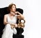 Mature sport muscular fashion woman in white dress sitting with gold gym dumbbells accessories weights in armchair