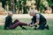 Mature sportsman touching injured leg of sportswoman sitting on lawn