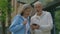 Mature sporty couple is standing on the street and man is showing his wife something in his smartphone. People