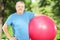 Mature sporty man holding a fitness ball in park