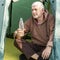 Mature sporty man sitting on a tent and holding a bottle of pure mineral water in his hands