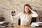 Mature tired woman with alarm clock at table in office. Time management concept