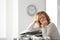 Mature tired woman with documents at table in office. Time management concept