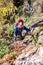 mature tourist walks along a narrow trail holding on to a rope over a cliff