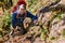 mature tourist walks along a narrow trail holding on to a rope over a cliff