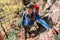 mature tourist walks along a narrow trail holding on to a rope over a cliff