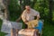 Mature Ukrainian peasant holding frame with bees while working in own bee yard