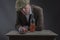 Mature Victorian gangster drinking whisky and leaning against a table