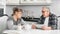 Mature wife and husband talking during coffee break at white kitchen interior