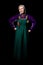 Mature woman in antique clothes posing in full growth, hands on hips. A vibrant mix of purple and green