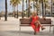 Mature woman, beautiful, blonde, in a red dress, smiling, happy and flirtatious, sitting on a wooden bench. Concept beauty,