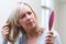 Mature Woman With Brush Concerned About Hair Loss