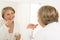 Mature woman brushing teeth look bathroom mirror