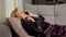Mature woman calls boss to tell about illness lying on sofa