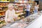 Mature woman choosing frozen food in supermarket. Young woman purchasing goods in grocery store