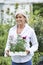 Mature Woman Choosing Plants At Garden Center