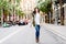 Mature woman in coat walking on a lighted city street, full legth