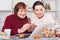 Mature woman and daughter at table using laptop