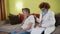 Mature woman doctor holding stethoscope examining senior grandma patient at home. Female physician listens to aged