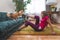 Mature woman doing abdominal exercise, her ginger cat reaches for the owner`s leg