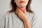 Mature woman doing thyroid self examination on light background, closeup