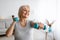 Mature woman exercising at home with two dumbbells