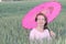 Mature woman finding shade under pink umbrella