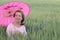 Mature woman finding shade under pink umbrella