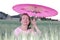 Mature woman finding shade under pink umbrella