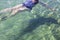 A mature woman floats on her back in clear sea water, where her shadow is visible on the bottom. Sea holiday