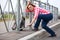 Mature woman get through road fence with her backpack. Urban roadside and pedestrian zone