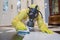 Mature woman in Haz Mat suit scrubbing floor with brush