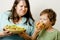 Mature woman holding salad and little cute boy with hamburger teasing close up, family food