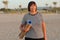 mature woman holding a sports mat and preparing to practice yoga outdoors on sea beach. Happy mature overweight woman