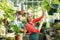 Mature woman inspecting potted plants at greenhouse