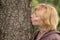 Mature woman kissing tree trunk