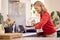 Mature Woman In Kitchen At Home Cooking Meal Following Recipe On Digital Tablet