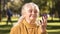 Mature woman looking at her reflection in compact mirror sitting in park