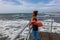 Mature woman looking out at a rough ocean on a windy day with her scarf flying in the wind