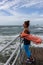 Mature woman looking out at a rough ocean on a windy day with her scarf flying in the wind