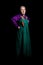 Mature woman in old purple and green clothes, with brooches in the form of turtles, posing. Full-length portrait, half-turn