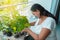 Mature woman among the plants on her balcony. People, gardening, planting and concept of the profession