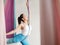 Mature woman pose in hammock performing aerial yoga or flying yoga exercise against white wall background in yoga studio room.