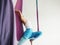 Mature woman pose in hammock performing aerial yoga or flying yoga exercise against white wall background in yoga studio room.