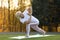 Mature woman practicing yoga on grass in park